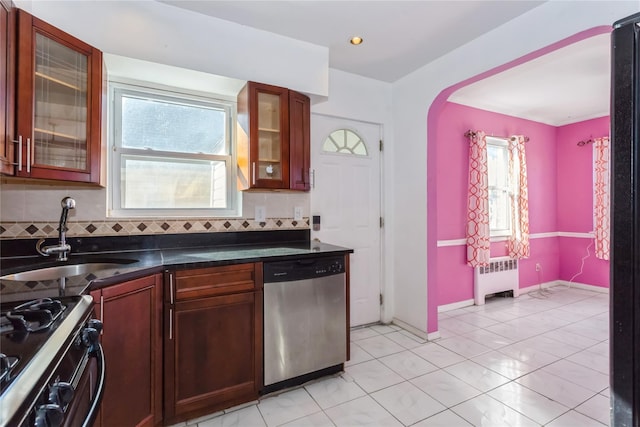 kitchen with dark countertops, radiator, decorative backsplash, stainless steel dishwasher, and a sink