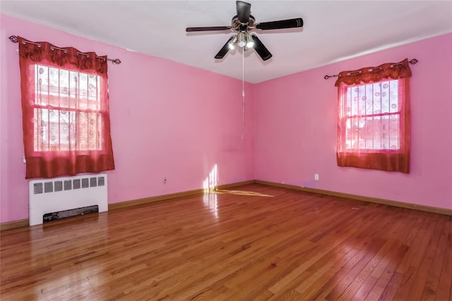 spare room with radiator, ceiling fan, baseboards, and hardwood / wood-style flooring