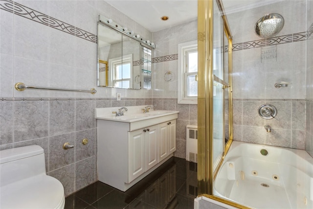 bathroom with tile walls, toilet, radiator heating unit, a combined bath / shower with jetted tub, and a sink