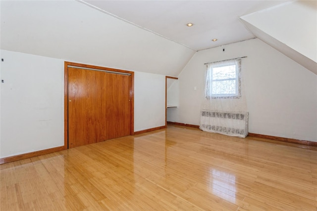 additional living space featuring vaulted ceiling, light wood finished floors, and baseboards