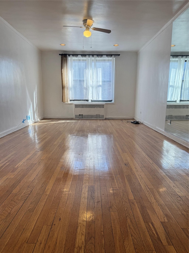 empty room featuring ornamental molding, radiator, wood-type flooring, and a ceiling fan