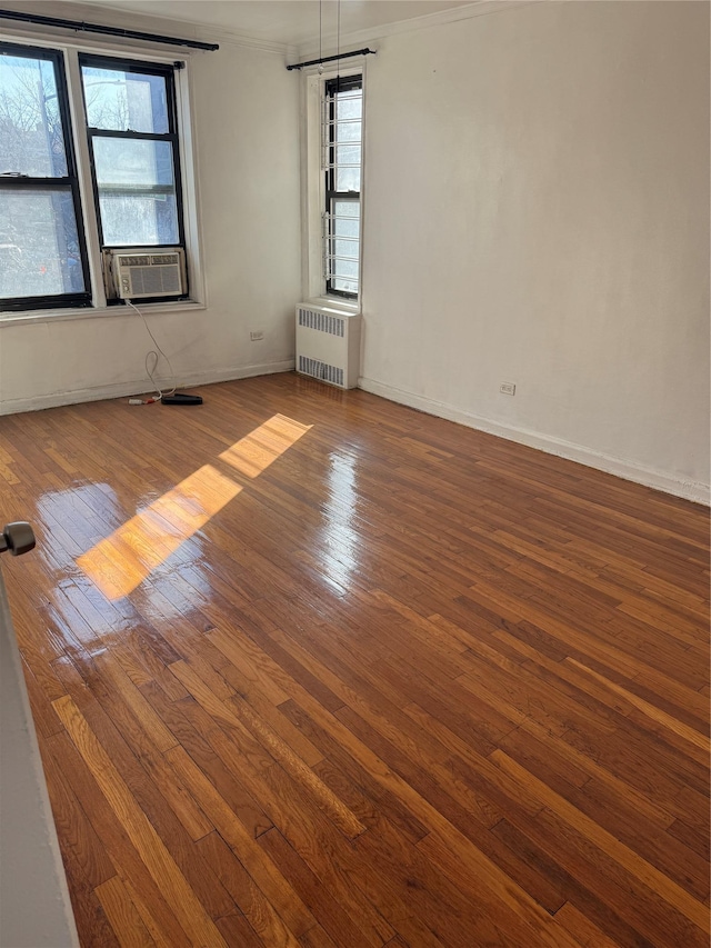 spare room featuring baseboards, radiator, hardwood / wood-style floors, crown molding, and cooling unit