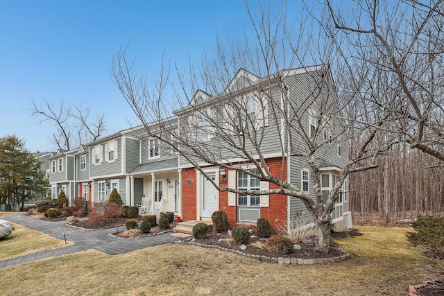 colonial inspired home featuring aphalt driveway, brick siding, and a front lawn