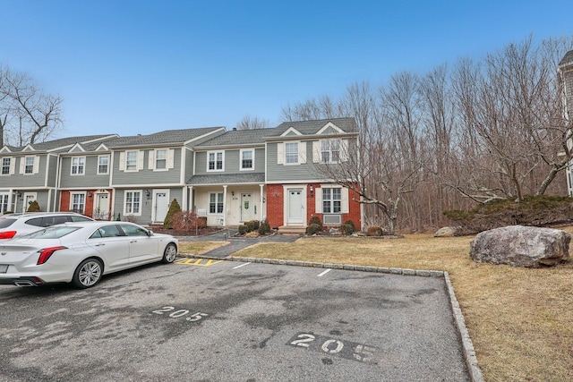 view of property with uncovered parking, brick siding, a front yard, and a residential view