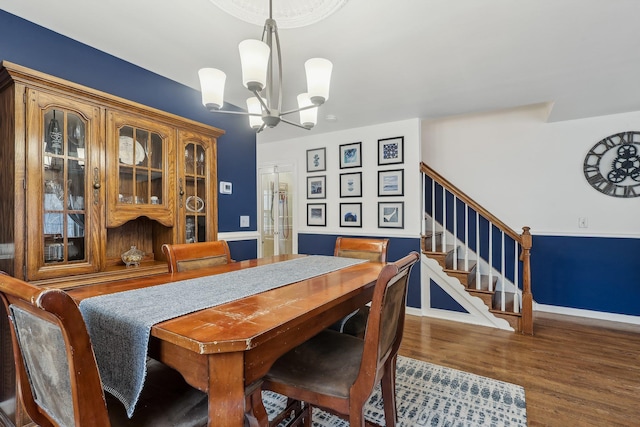 dining room with a chandelier, stairway, baseboards, and wood finished floors