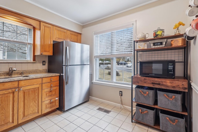 kitchen featuring visible vents, backsplash, freestanding refrigerator, a sink, and black microwave