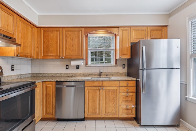 kitchen featuring brown cabinets, a sink, stainless steel appliances, under cabinet range hood, and backsplash