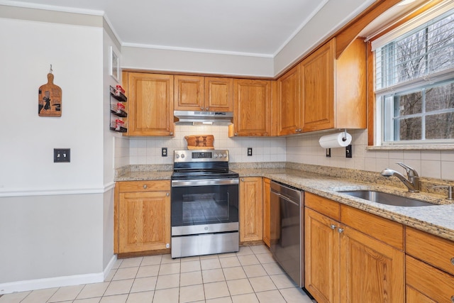 kitchen featuring decorative backsplash, appliances with stainless steel finishes, light stone countertops, under cabinet range hood, and a sink