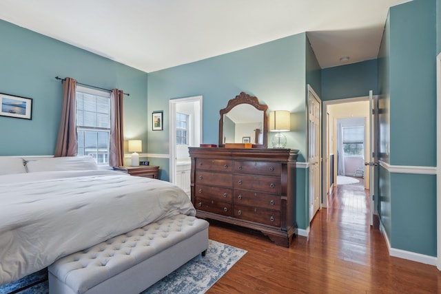 bedroom featuring ensuite bathroom, wood finished floors, and baseboards