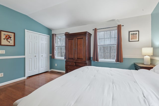 bedroom featuring lofted ceiling, multiple windows, baseboards, and wood finished floors