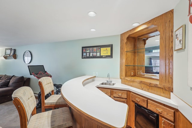 kitchen with brown cabinetry, open floor plan, light countertops, a sink, and recessed lighting