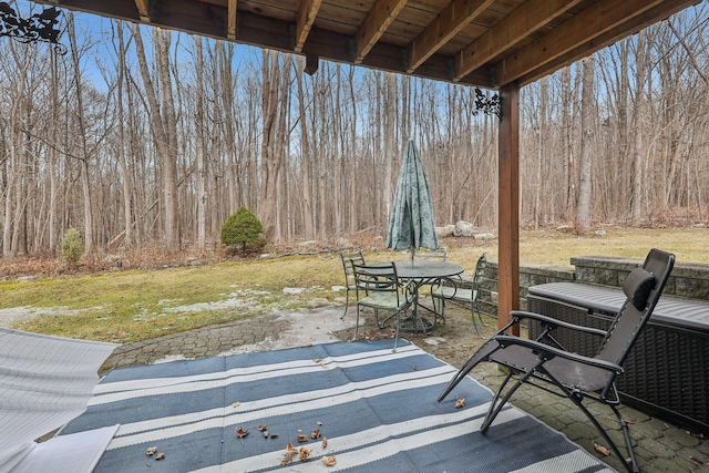 view of patio with outdoor dining space and a wooded view