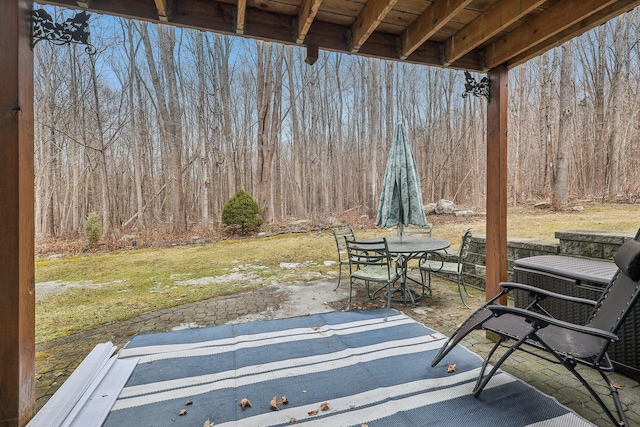 view of patio with outdoor dining space and a wooded view