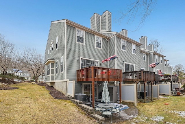 back of house featuring a chimney, a wooden deck, a lawn, and central air condition unit