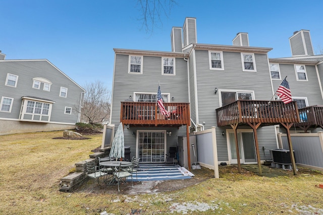 back of house with a chimney, a lawn, a patio area, cooling unit, and a wooden deck