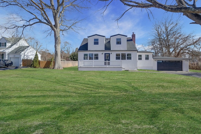 view of front of home featuring a chimney, fence, a detached garage, and a front yard