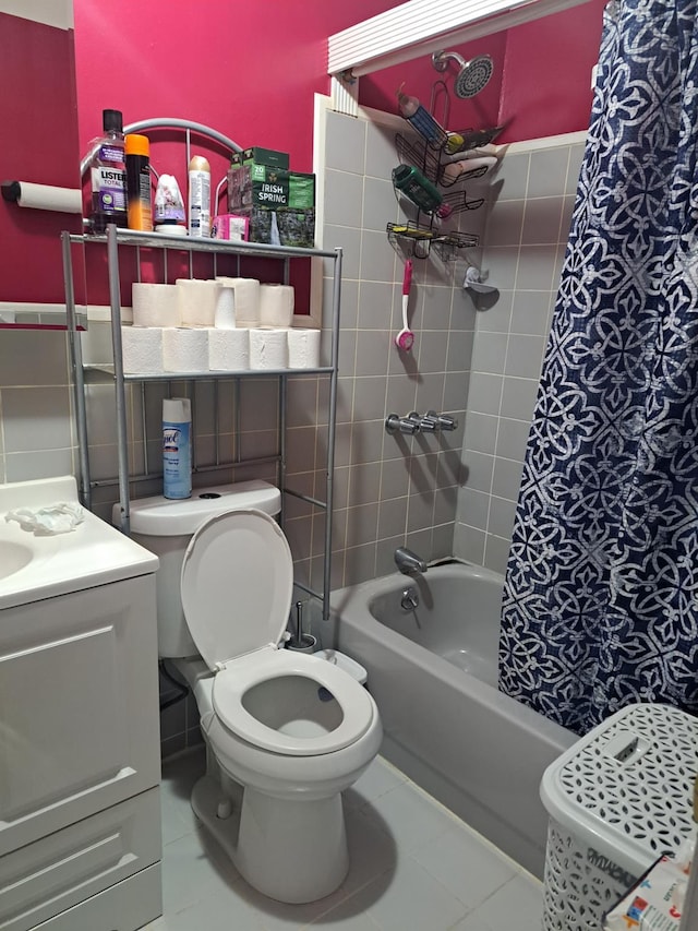 full bathroom with tile patterned flooring, toilet, tile walls, wainscoting, and shower / bathtub combination with curtain