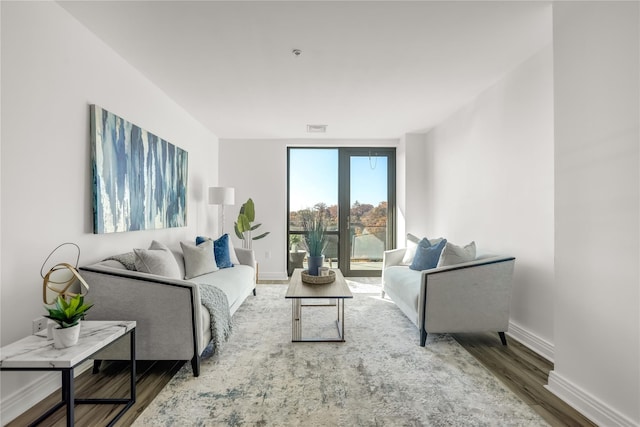 living room with baseboards, visible vents, and wood finished floors