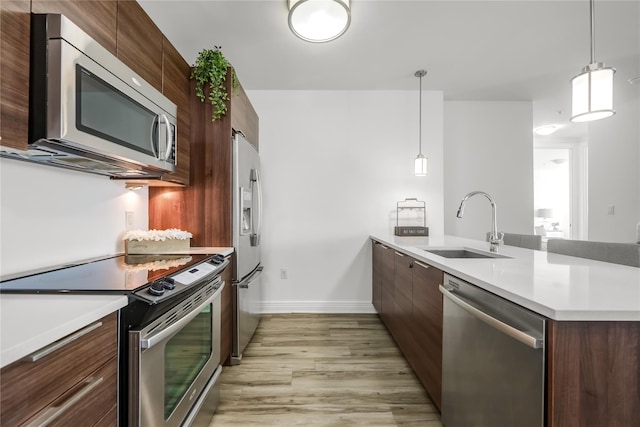 kitchen featuring light countertops, appliances with stainless steel finishes, a sink, modern cabinets, and a peninsula