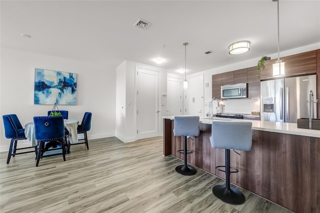 kitchen with visible vents, appliances with stainless steel finishes, light countertops, and a kitchen breakfast bar