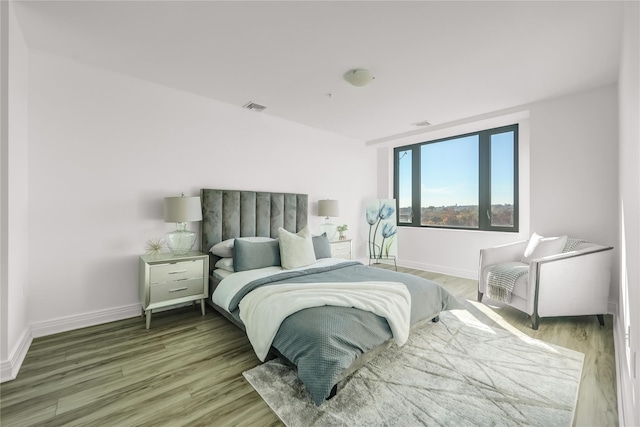 bedroom with wood finished floors, visible vents, and baseboards