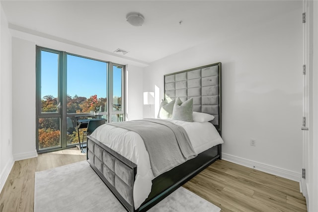 bedroom with light wood-style flooring, visible vents, and baseboards