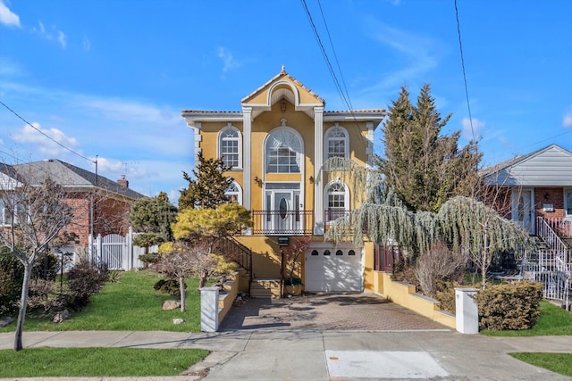 view of front of property with driveway, an attached garage, stairs, fence, and stucco siding