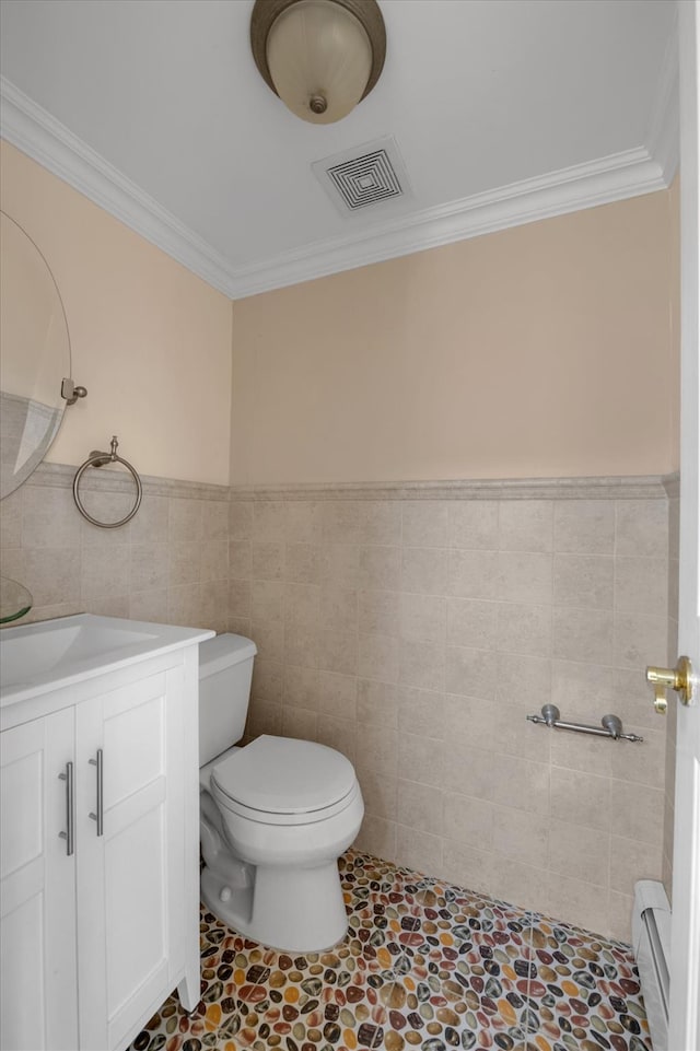 bathroom featuring toilet, vanity, visible vents, tile walls, and baseboard heating