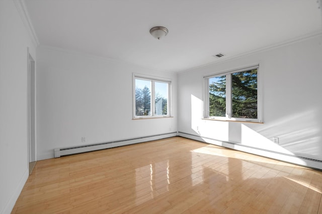 spare room with a baseboard radiator, wood finished floors, visible vents, and crown molding