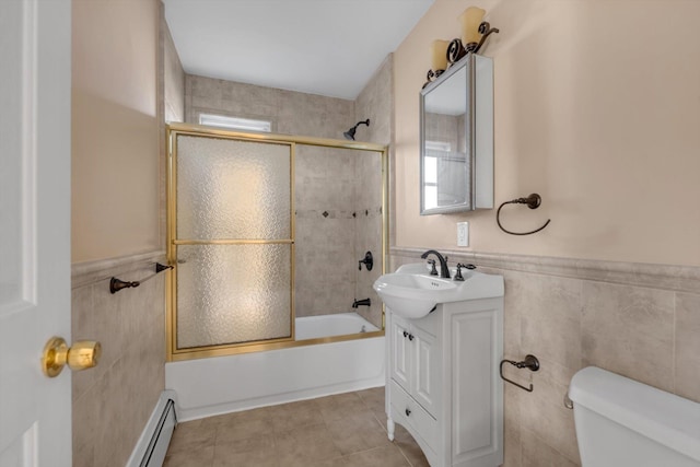 bathroom featuring toilet, shower / bath combination with glass door, wainscoting, and tile walls