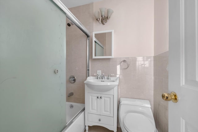 bathroom with enclosed tub / shower combo, toilet, tile walls, and vanity