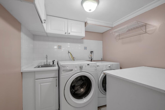 clothes washing area featuring crown molding, a sink, cabinet space, and washer and dryer