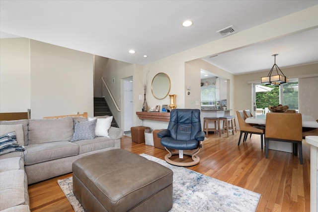 living room with stairway, light wood-type flooring, visible vents, and recessed lighting