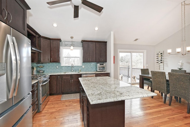 kitchen featuring dark brown cabinetry, appliances with stainless steel finishes, vaulted ceiling, and a sink