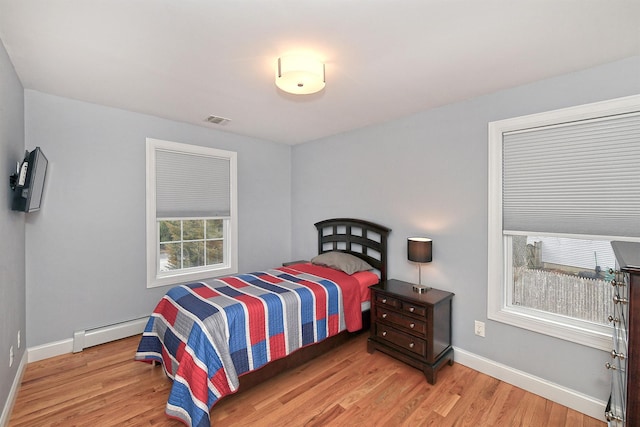 bedroom featuring baseboards, visible vents, light wood-style flooring, and baseboard heating