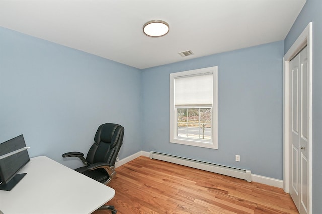 office featuring a baseboard heating unit, light wood-style flooring, visible vents, and baseboards