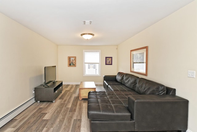 living room with a baseboard heating unit, wood finished floors, visible vents, and baseboards