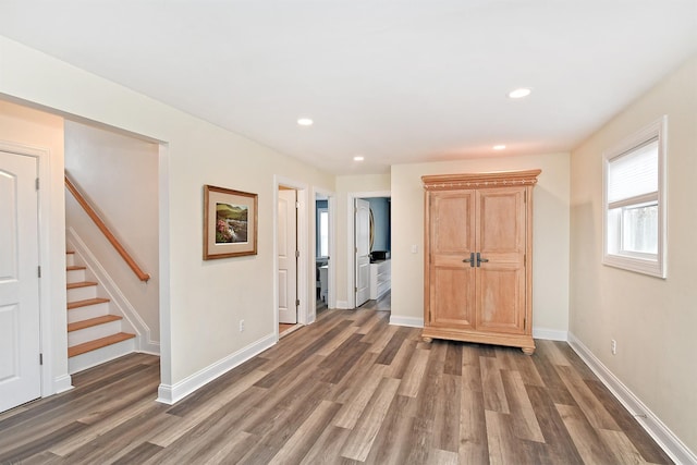 spare room featuring baseboards, stairway, and wood finished floors