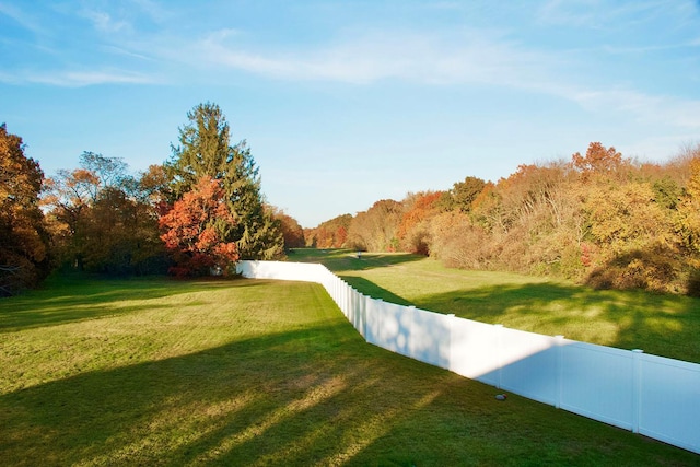 view of home's community featuring fence, a view of trees, and a yard