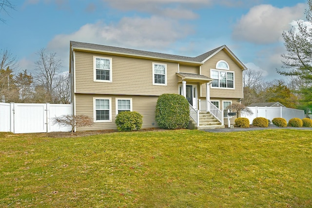 raised ranch with a gate, fence, and a front lawn