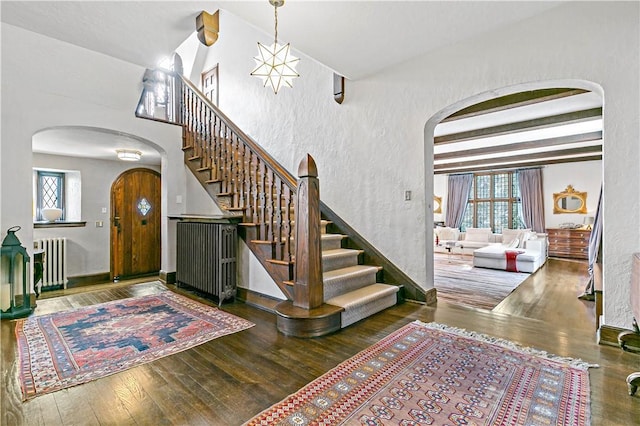 31 Old Army Rd, Scarsdale, NY 10583 - foyer entrance with a textured wall, stairway, radiator heating unit, arched walkways, and wood finished floors