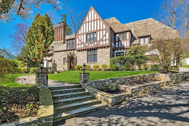 31 Old Army Rd, Scarsdale, NY 10583 - tudor home featuring a chimney, a front yard, stone siding, and stucco siding