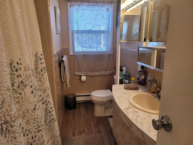 bathroom featuring toilet, a wainscoted wall, wood finished floors, tile walls, and baseboard heating