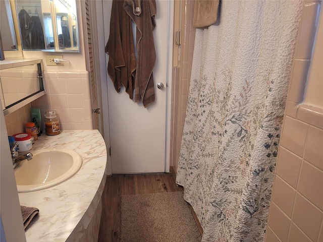 full bath with vanity, a shower with shower curtain, wood finished floors, and tile walls