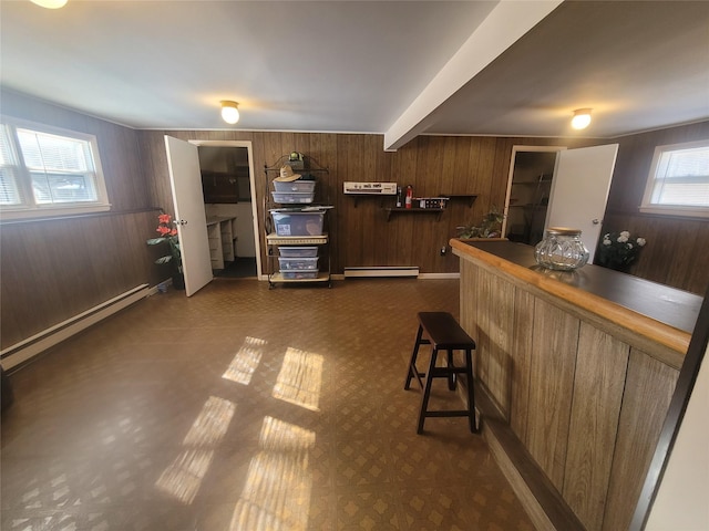 interior space featuring a baseboard heating unit, wood walls, baseboard heating, brown cabinetry, and beamed ceiling