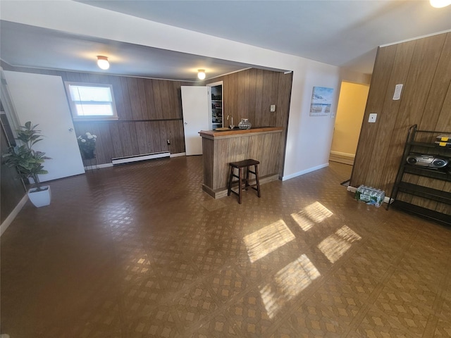 kitchen with a peninsula, dark floors, a baseboard radiator, and a kitchen breakfast bar