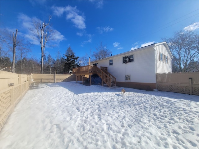 snow covered house featuring stairway, fence, and a wooden deck