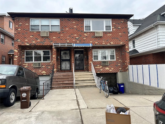 view of front of home featuring brick siding, fence, and a wall mounted AC