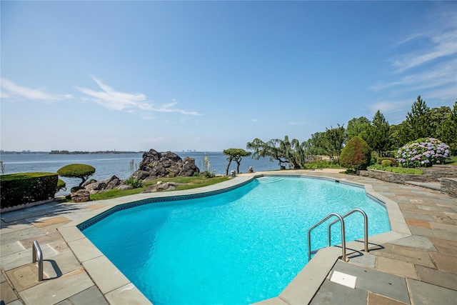 outdoor pool with a patio area and a water view