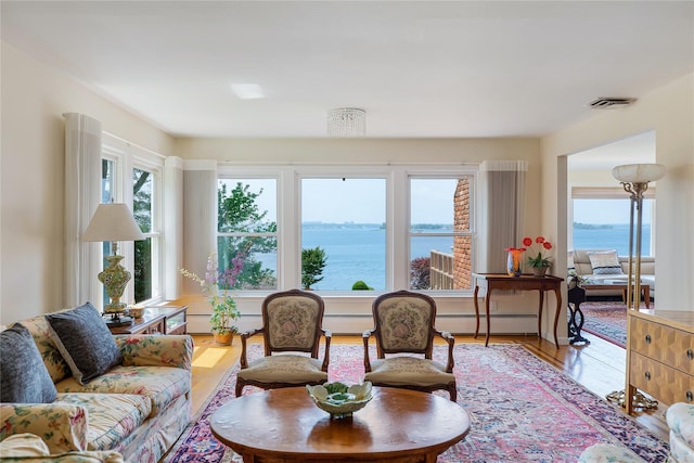 sunroom / solarium with visible vents, plenty of natural light, baseboard heating, and a water view